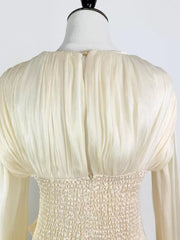 White ruffled mini dress with smocked corset waist detail and long sleeves.