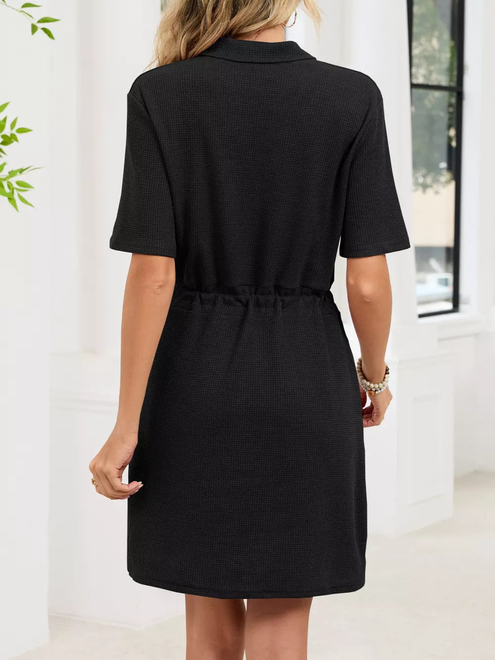 Black textured polo dress with short sleeves and adjustable drawstring waist.