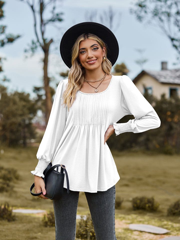 White peplum blouse with gathered yoke and smocked cuffs.