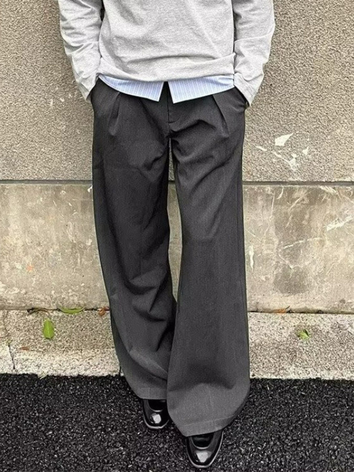 Men's gray wide-leg sweatpants with pleats and pockets, styled with a crewneck sweatshirt and collared shirt.