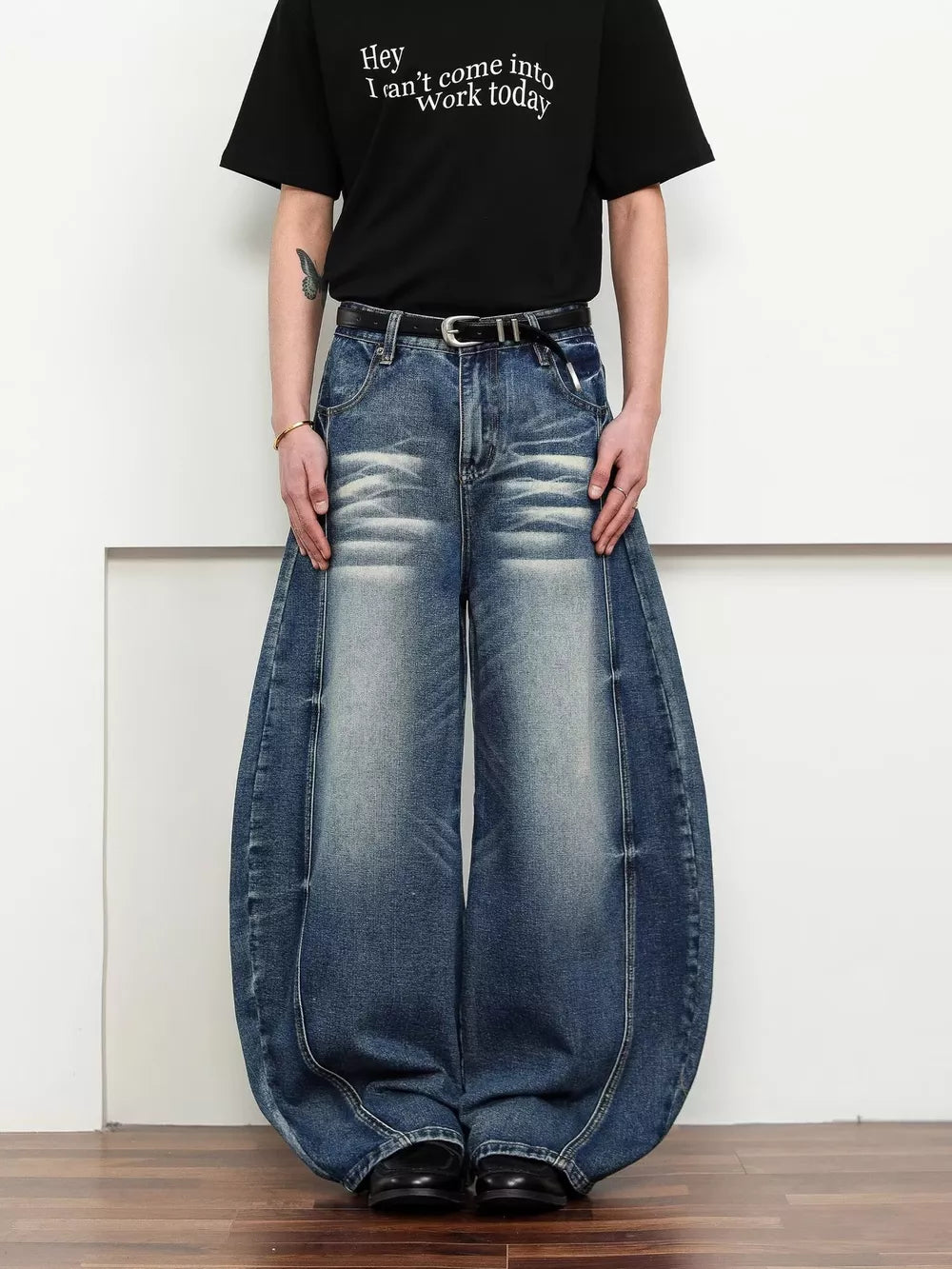 Belted wide leg jeans in dark blue denim with a balloon silhouette and distressed details.