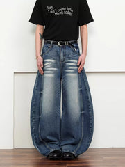 Belted wide leg jeans in dark blue denim with a balloon silhouette and distressed details.