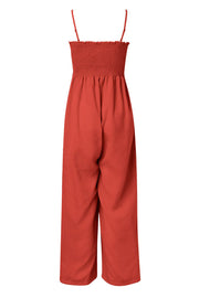 Orange-red smocked bodice palazzo jumpsuit with wide legs and spaghetti straps.