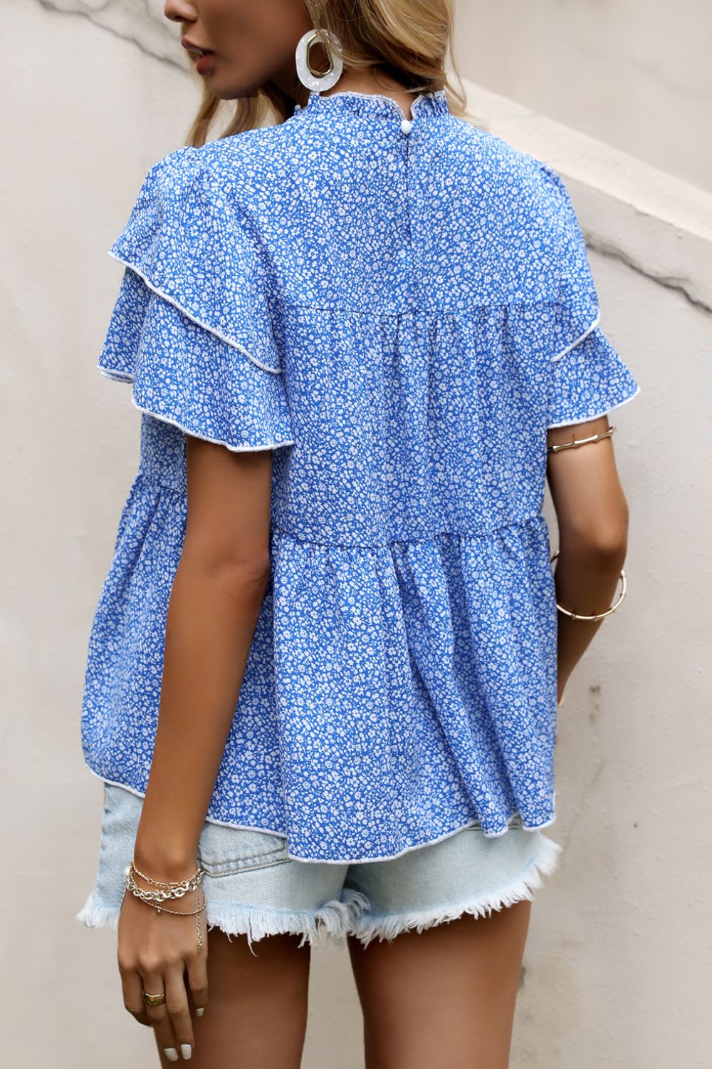 Sky blue floral peplum blouse with ruffled tiers and white trim, high neckline.