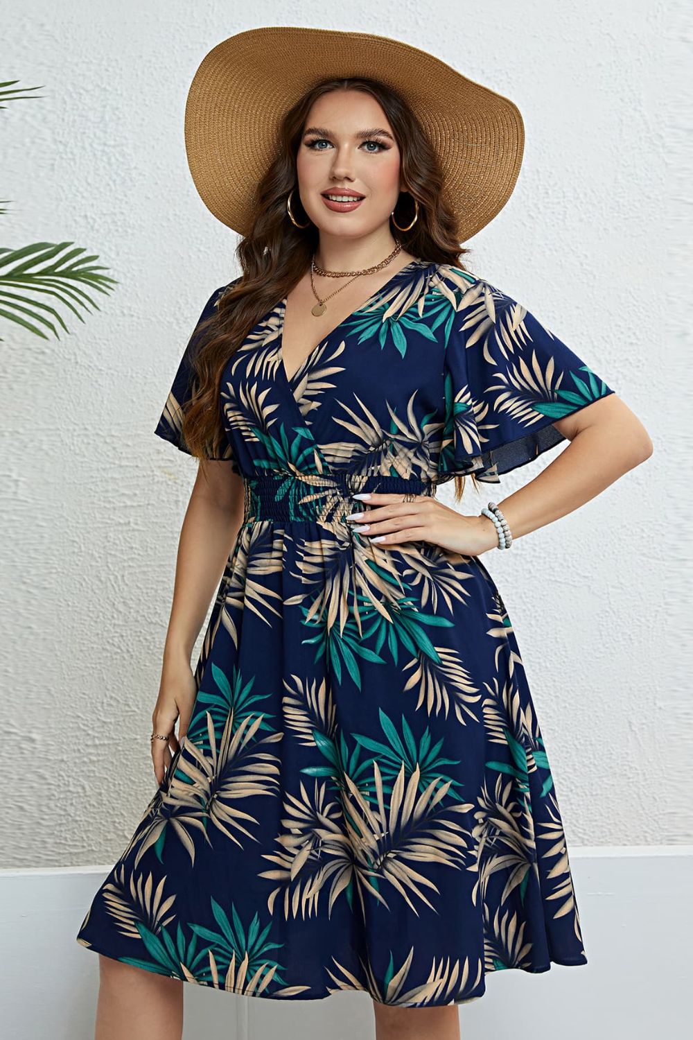 Navy empire waist midi dress with palm print, V-neck, flutter sleeves, and smocked waist.