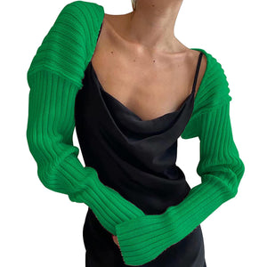 Green ribbed knit shrug with extended sleeves worn over a black slip dress.