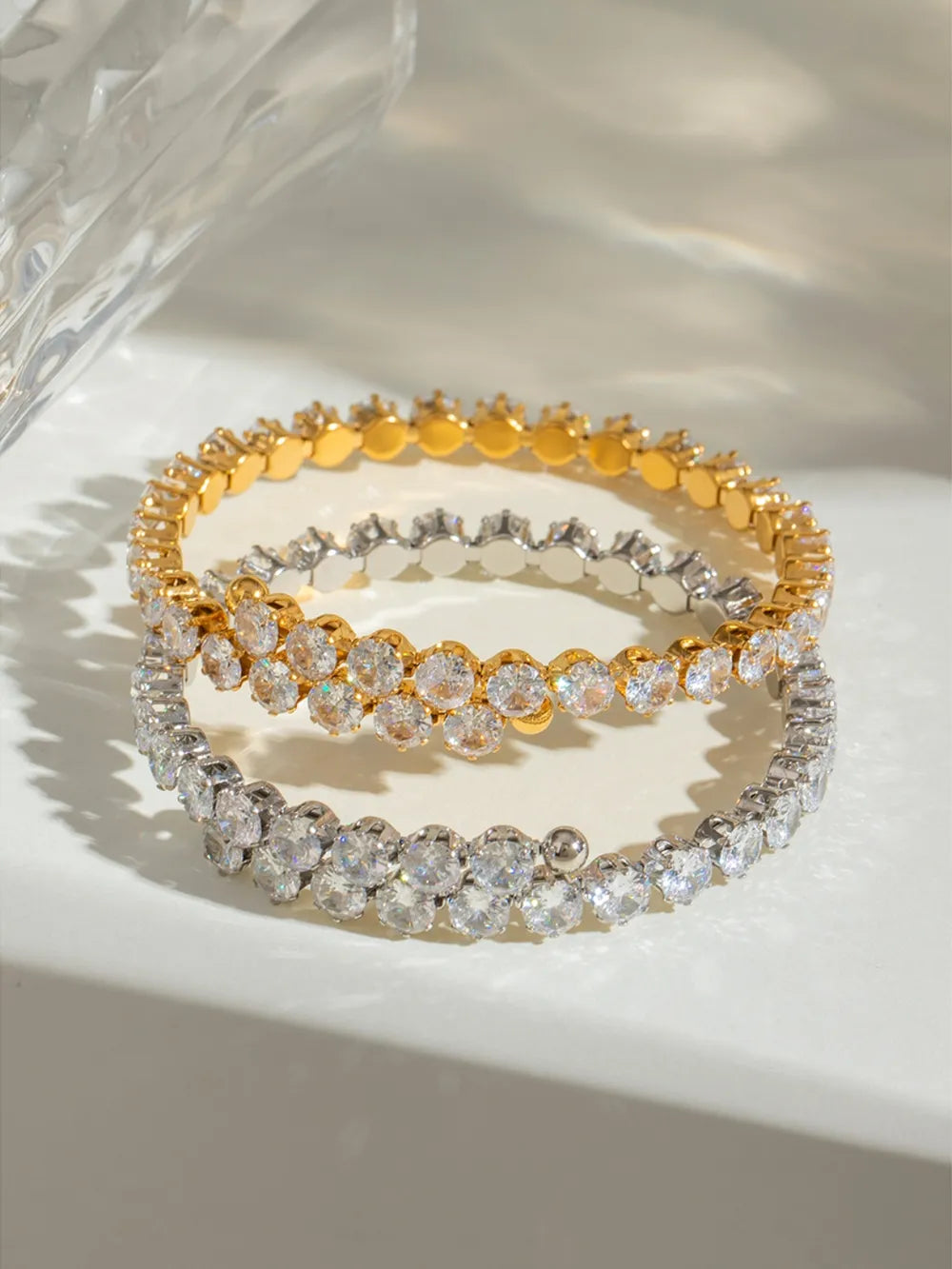 Double row pavé bangle bracelets in silver and gold with clear cubic zirconia stones.