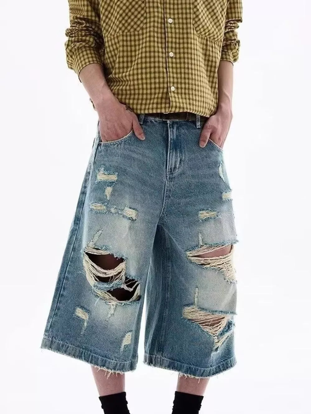 Distressed blue denim shorts for men with wide legs and raw hems.