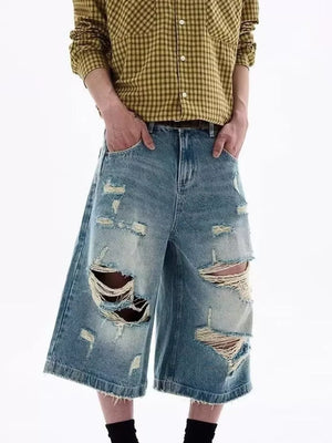 Distressed blue denim shorts for men with wide legs and raw hems.
