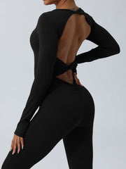 Black long sleeve sculpting jumpsuit with open back twist detail and ruched butt.