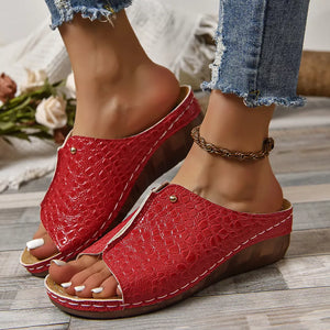 Red glossy crocodile-embossed wedge sandals with open toe and white stitching.