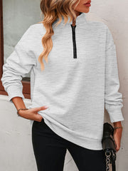 Light gray quarter-zip sweatshirt with black zipper detail and relaxed fit.