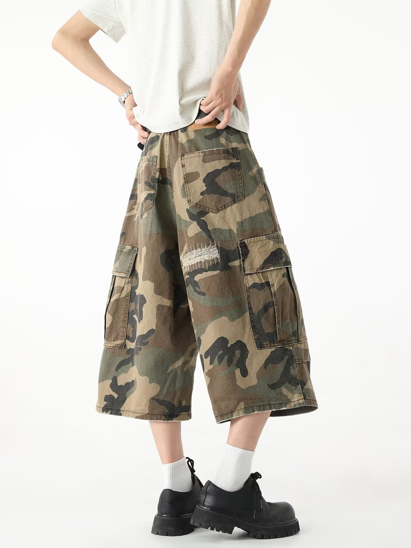 Men's camouflage cargo denim shorts with distressed details and multiple pockets.