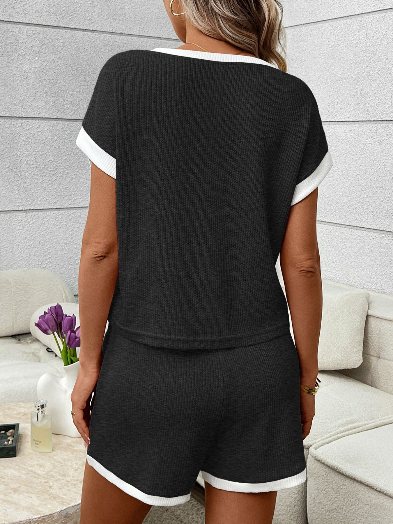 Black ribbed knit two-piece set with white trim, short sleeves, and shorts.