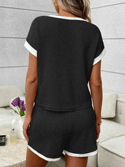 Black ribbed knit two-piece set with white trim, short sleeves, and shorts.