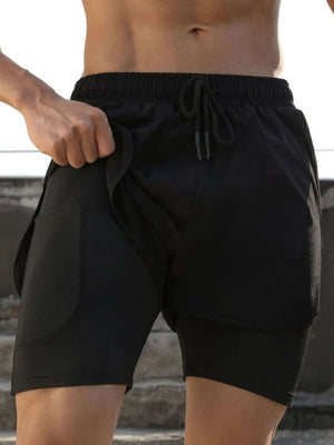 Black layered performance training shorts with built-in compression liner and drawstring waist.