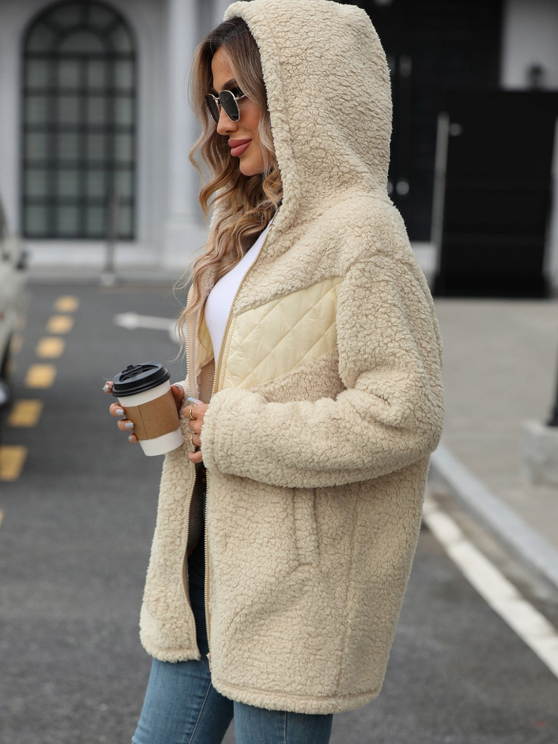 Cream teddy hoodie with quilted panel detail and zip front, worn open.