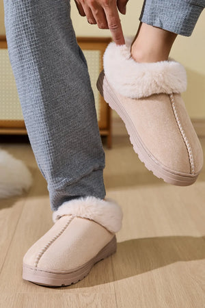Suede house slippers in beige with fluffy shearling trim and contrast stitching detail.
