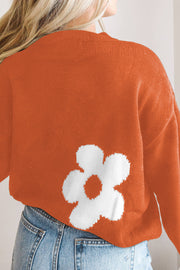 Orange acrylic crewneck sweater with white floral intarsia pattern detail.