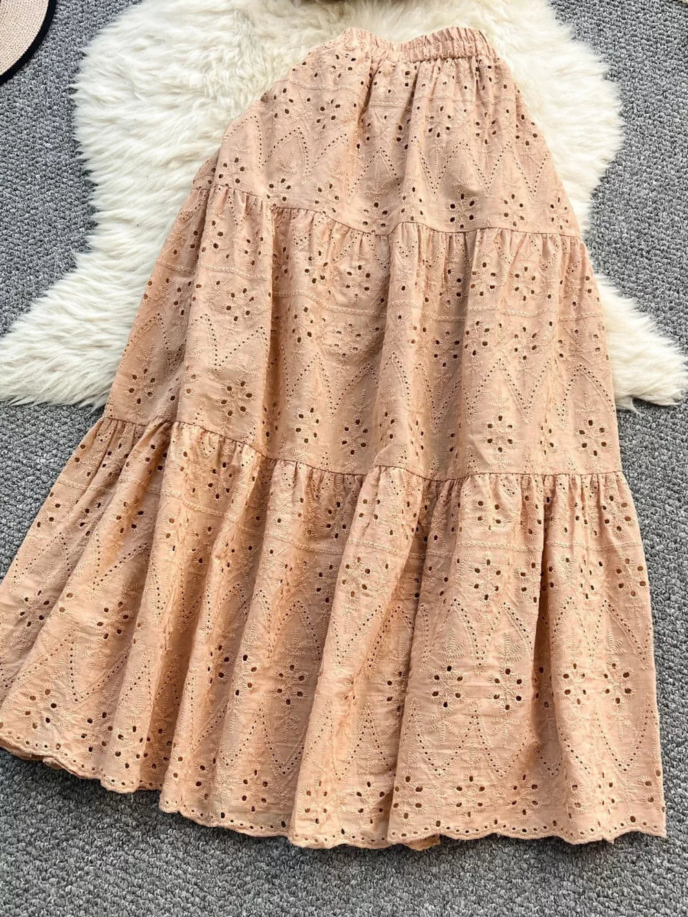 Apricot eyelet maxi skirt with tiered ruffles and elastic waistband.