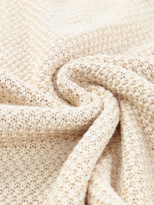 Beige knit sweater with a V-neck and subtle heart pattern, made of cotton and acrylic blend.