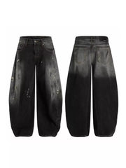 Men's wide leg jeans in distressed black denim with paint splatters and a gradient wash.