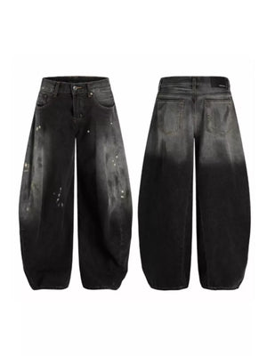 Men's wide leg jeans in distressed black denim with paint splatters and a gradient wash.