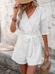 White eyelet wrap romper with tie waist and short sleeves.