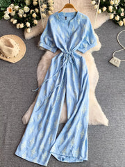 Blue floral print drawstring jumpsuit with short sleeves and wide legs.