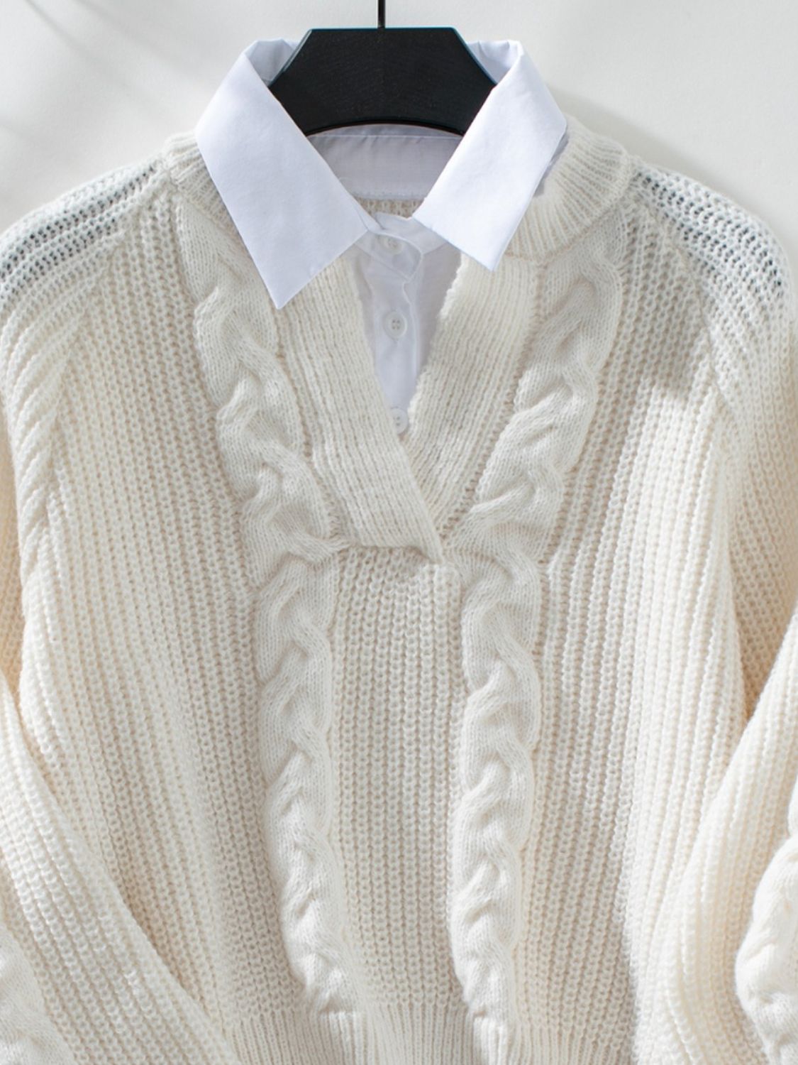 Cream cable knit V-neck sweater with textured details and a white collared shirt underneath.