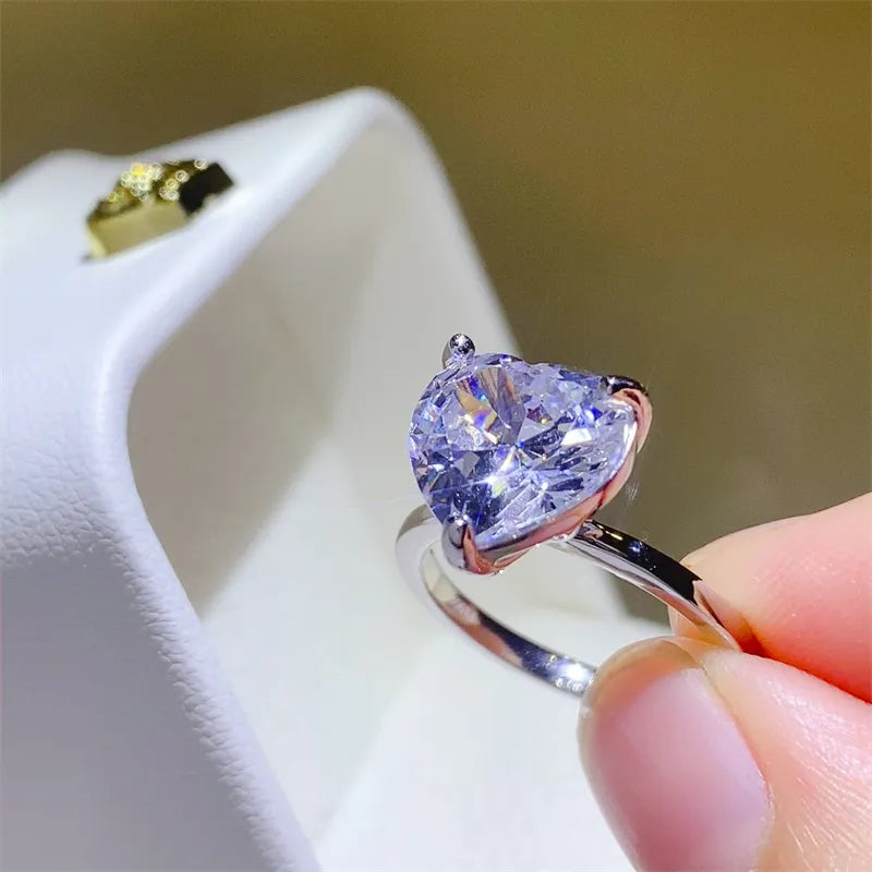Silver ring with a large, sparkling heart-cut moissanite stone.