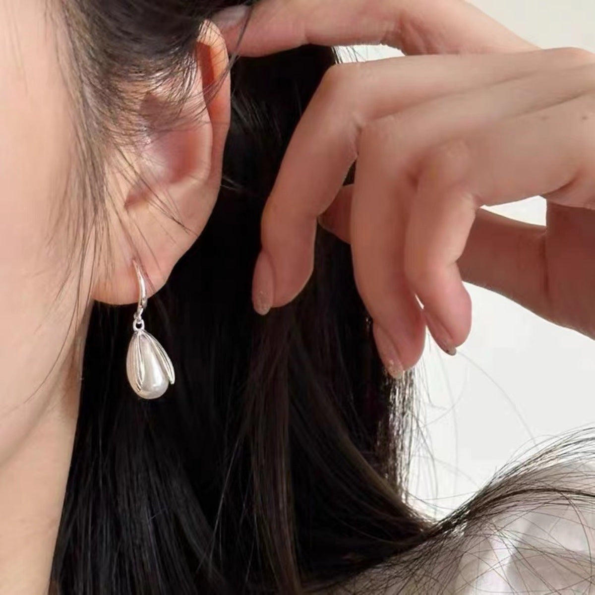 Lustrous pearl drop earrings in silver with a delicate petal design.