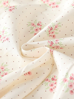 Cream cotton toddler dress fabric with pink floral bouquets and brown polka dots.
