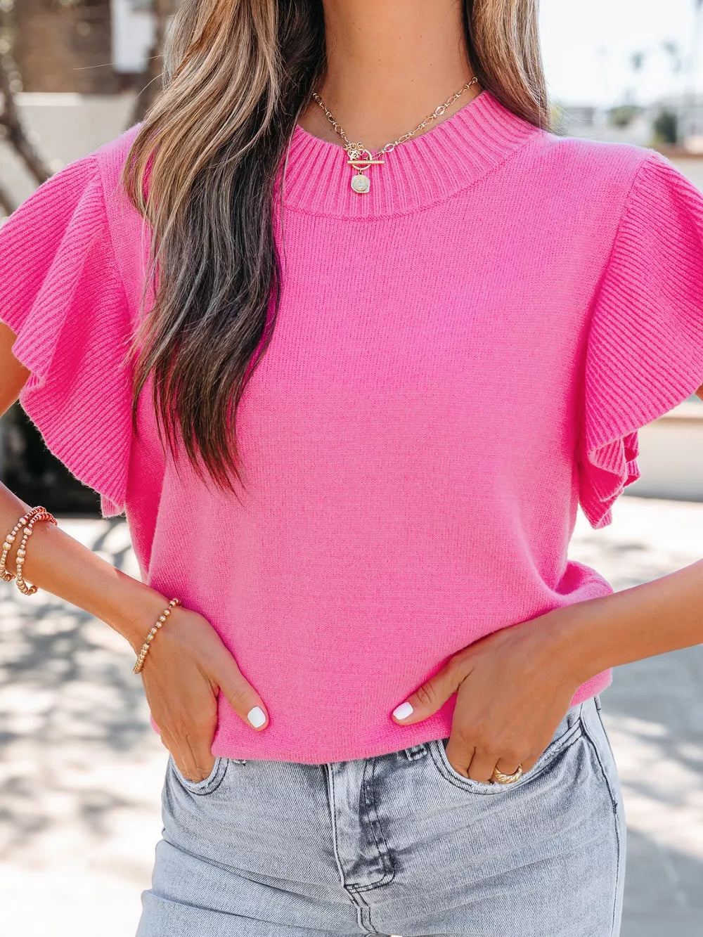 Pink knit top with ruffled short sleeves and mock neckline.