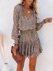 Leopard print tiered mini dress with ruffled neckline and cuffs, smocked waist, and long sleeves.