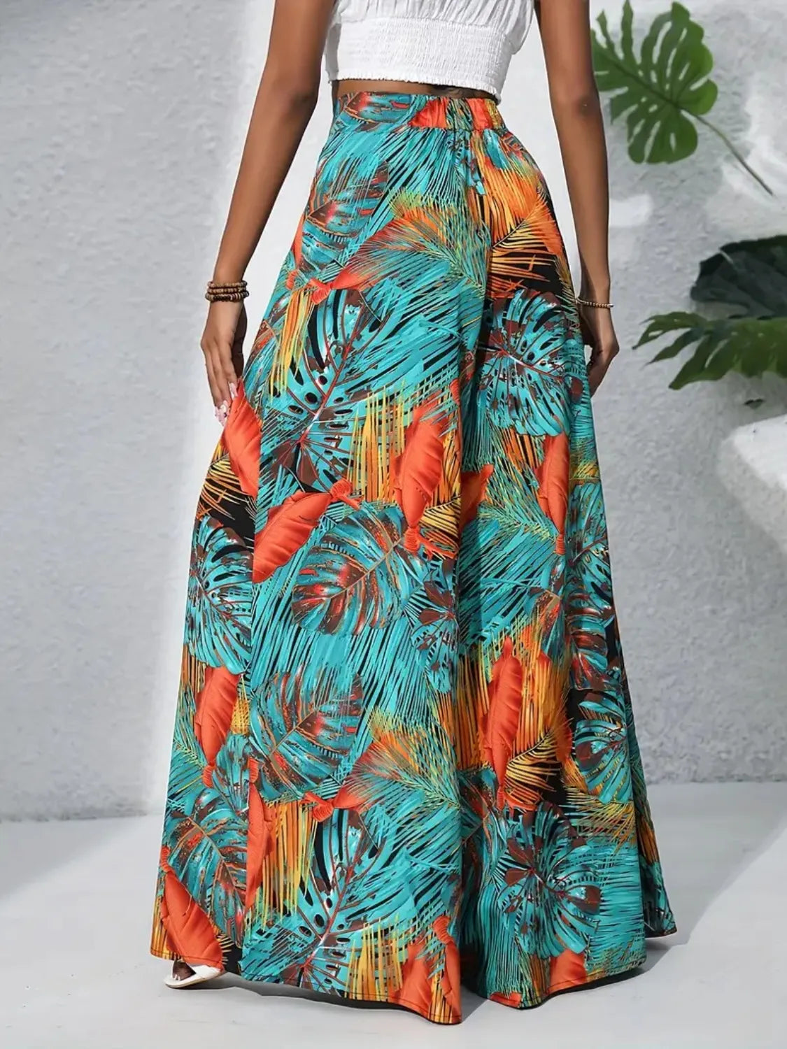 Palazzo trousers in tropical leaf print, teal, orange-red, and white.