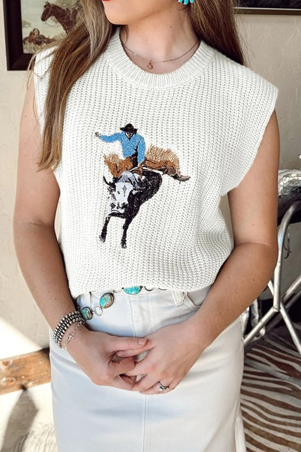 White acrylic knit vest with rodeo graphic, crew neck, sleeveless, relaxed fit.