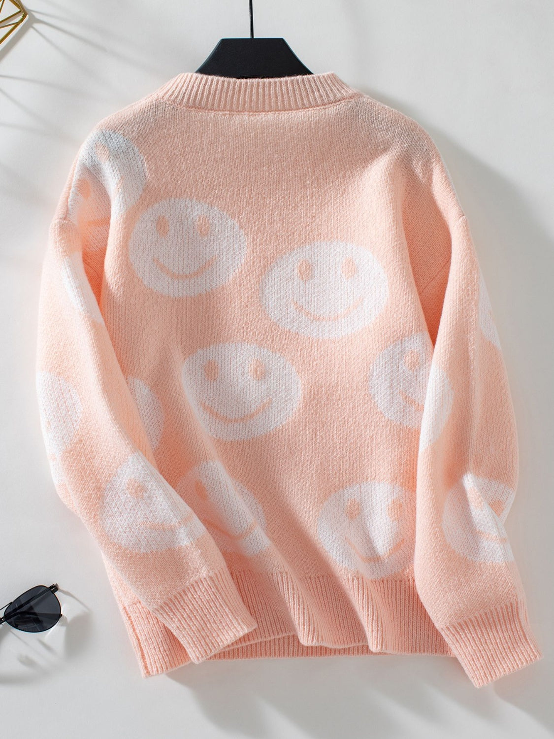 Watermelon pink intarsia knit sweater with allover white smiley faces.