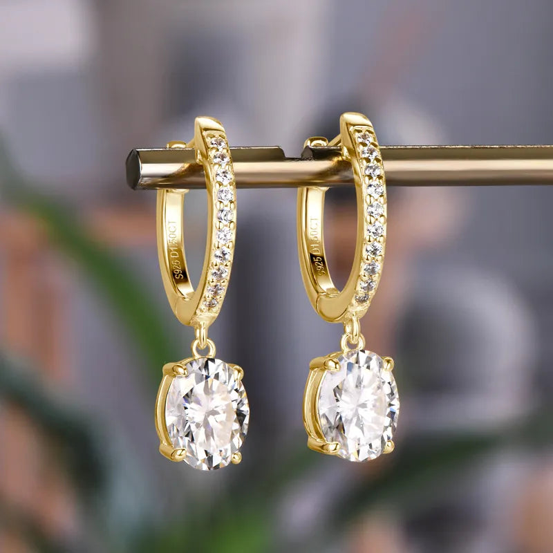 Gold pavé hoop and oval moissanite drop earrings with clear stones.