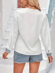 White V-neck blouse with embroidered trim on cuffs and subtle puff sleeves.