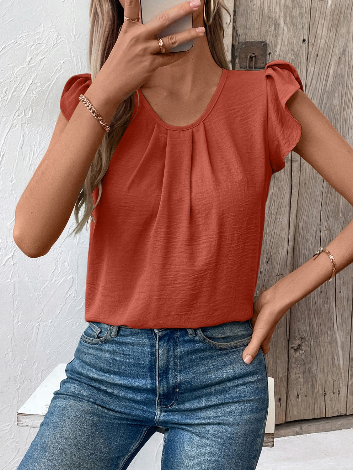 Terracotta pleated yoke flutter sleeve blouse with a scoop neck.