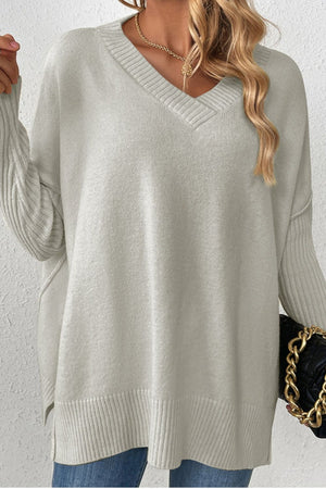 Gray v-neck knit sweater with ribbed cuffs and asymmetric hemline.