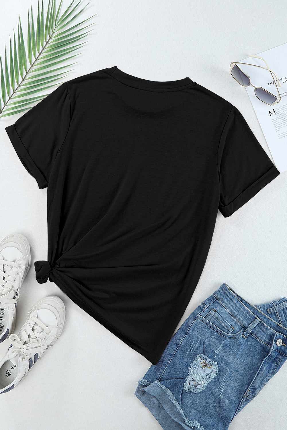 Black t-shirt with cuffed sleeves and a knotted hem, styled with denim shorts and sneakers.