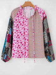 Boho patchwork print blouse with floral and geometric patterns, tie neck, and bubble sleeves.