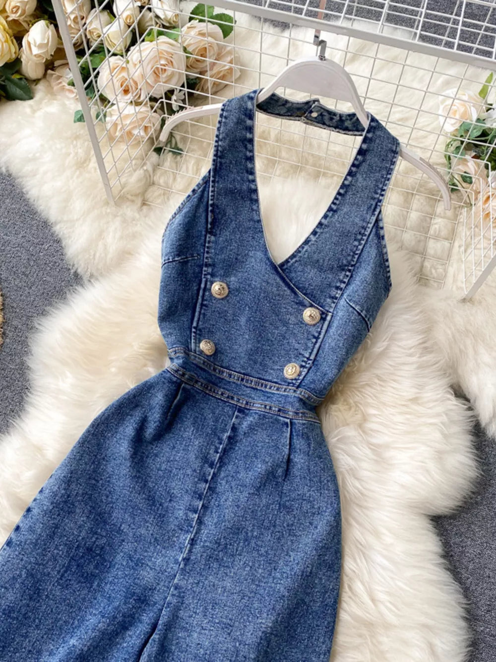 Blue denim halter neck wide-leg jumpsuit with double-breasted gold buttons.