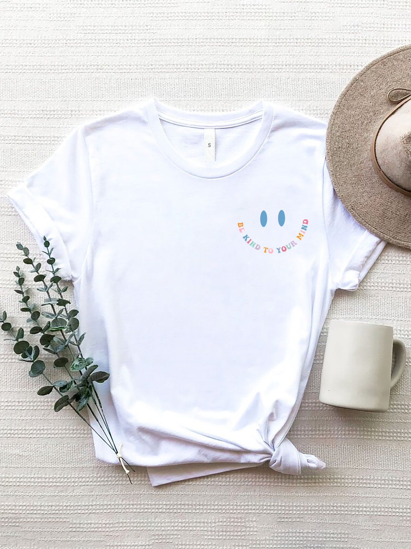 White t-shirt with a smiley face graphic and "Be Kind To Your Mind" text.