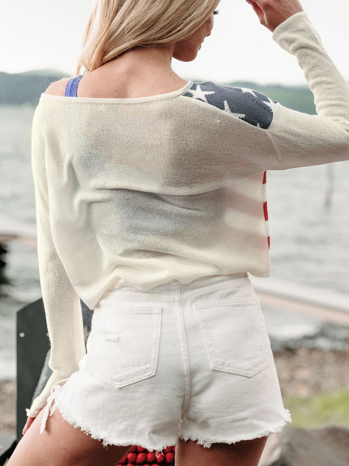 Ivory off-shoulder knit sweater with American flag detail on shoulder and sleeve.