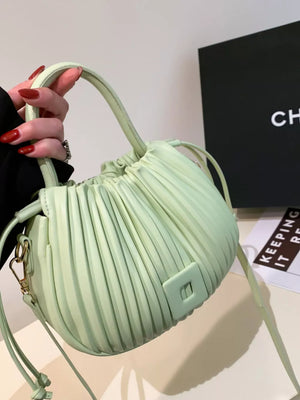 Light green pleated bucket bag with drawstring closure and square detail.