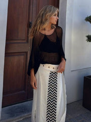 Black textured knit batwing cover-up with wide sleeves worn over a black bikini top.
