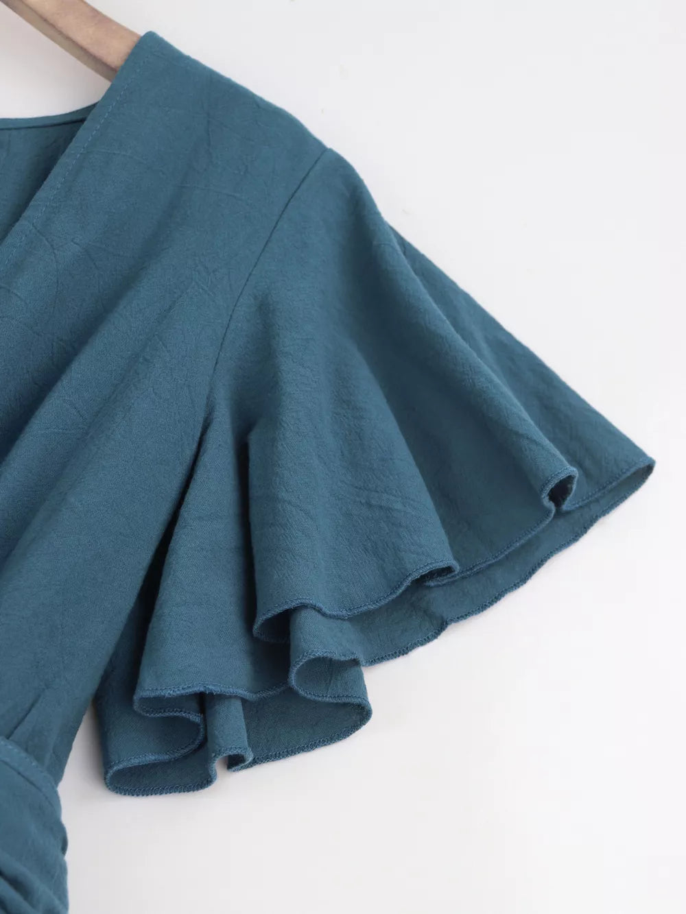 Haze blue cotton romper with flutter sleeves and tie waist detail.